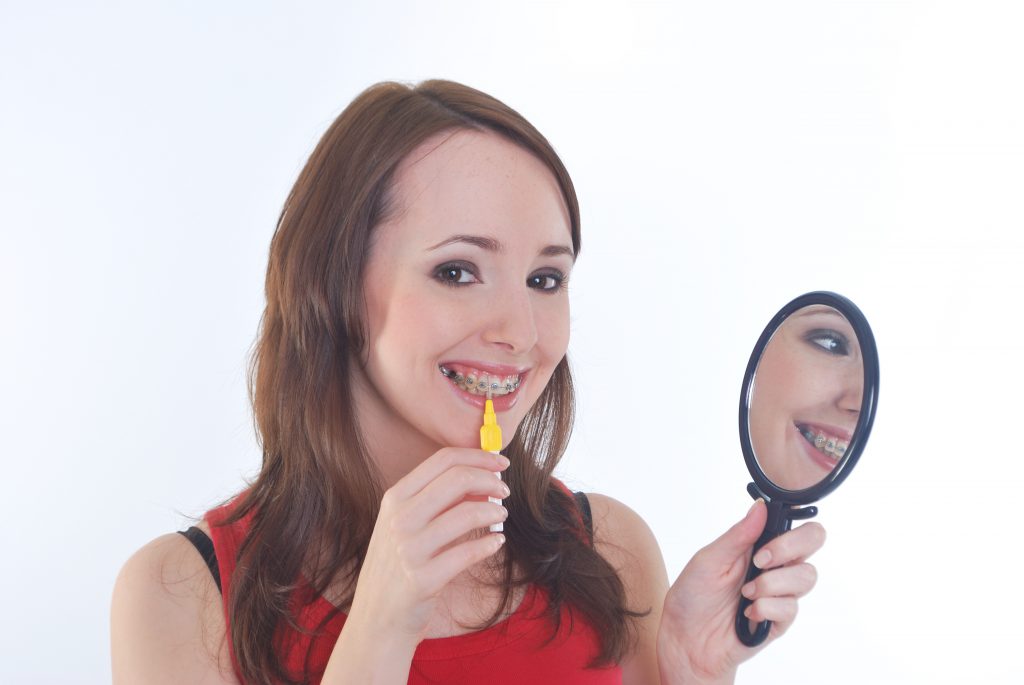 girl with braces cleaning teeth